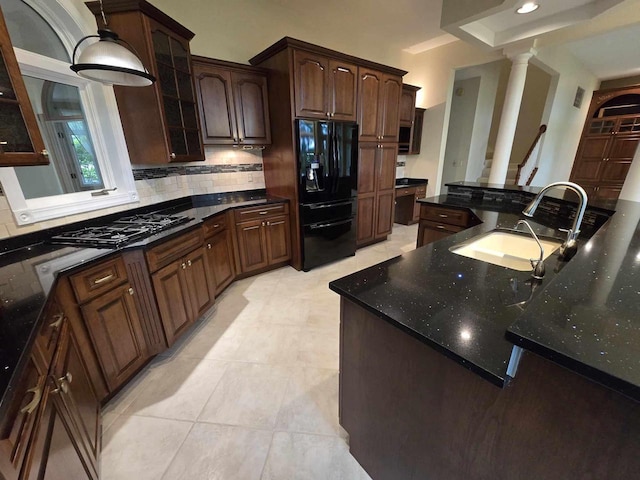 kitchen featuring sink, dark stone counters, decorative backsplash, dark brown cabinetry, and black appliances