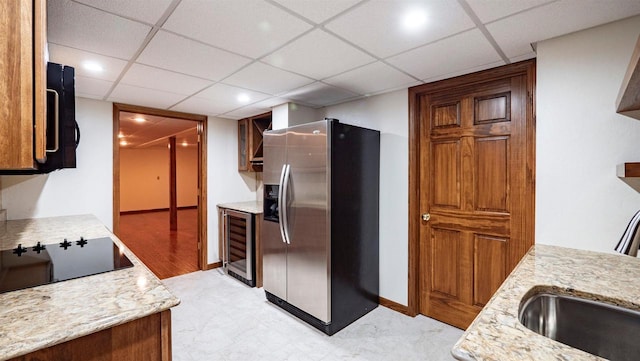 kitchen with stainless steel refrigerator with ice dispenser, beverage cooler, and black electric cooktop