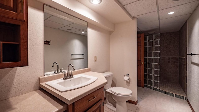 bathroom featuring walk in shower, tile patterned floors, toilet, a paneled ceiling, and vanity