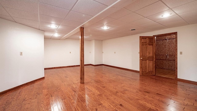 basement with hardwood / wood-style floors and a paneled ceiling