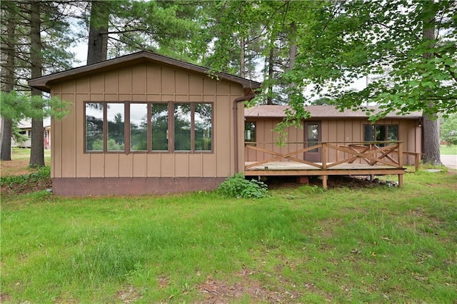 back of property featuring a deck and a lawn