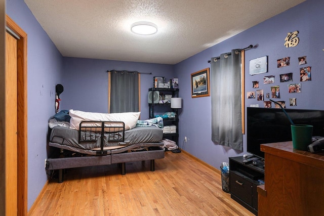 bedroom featuring light hardwood / wood-style floors and a textured ceiling