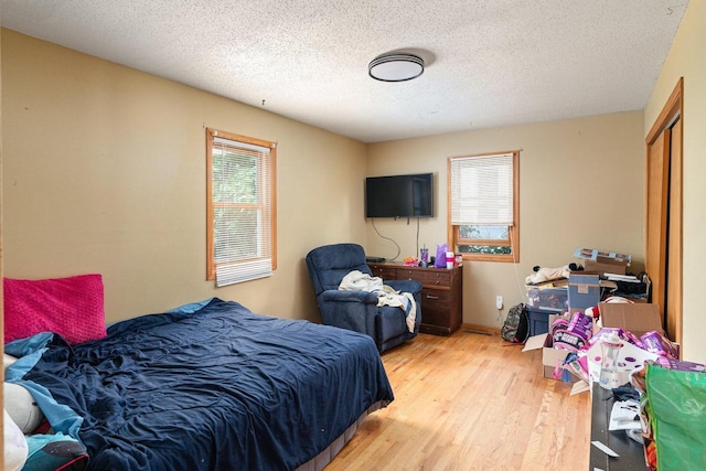 bedroom featuring light wood-type flooring, a textured ceiling, and a closet