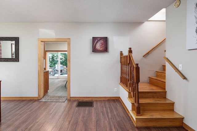 stairs featuring a textured ceiling and hardwood / wood-style flooring