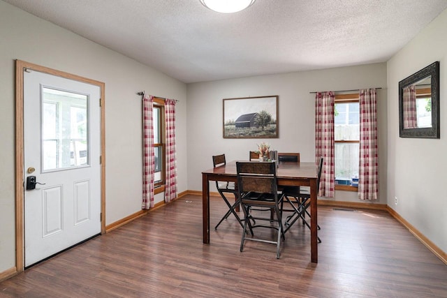 dining space with a textured ceiling and dark wood-type flooring