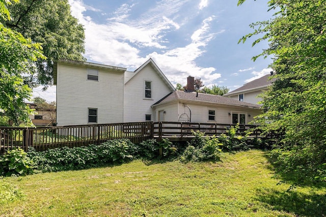 back of house featuring a lawn and a deck