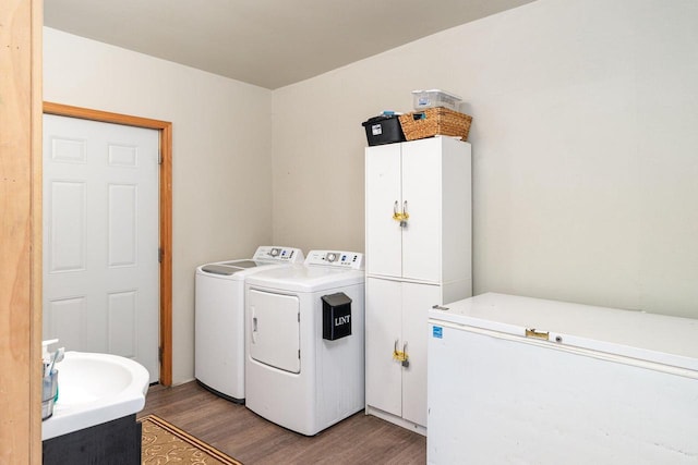 laundry room with hardwood / wood-style floors, washing machine and dryer, and cabinets