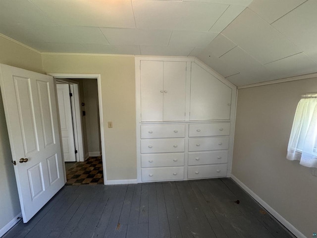 unfurnished bedroom featuring crown molding and dark wood-type flooring