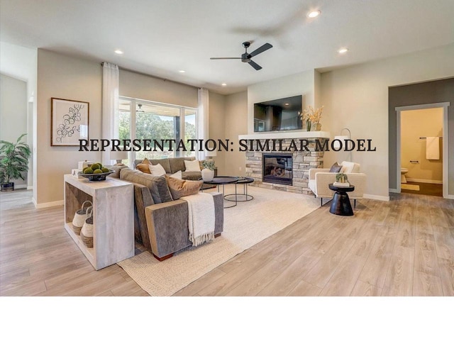 living room with ceiling fan, light hardwood / wood-style floors, and a stone fireplace