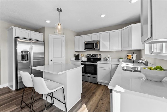 kitchen with pendant lighting, sink, a kitchen island, white cabinetry, and stainless steel appliances