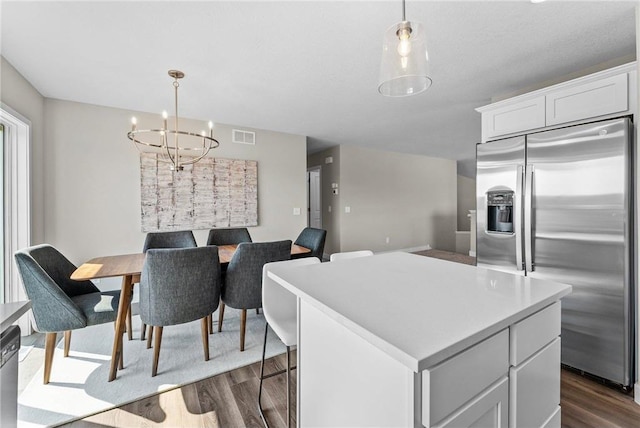 kitchen with appliances with stainless steel finishes, a center island, decorative light fixtures, and white cabinetry