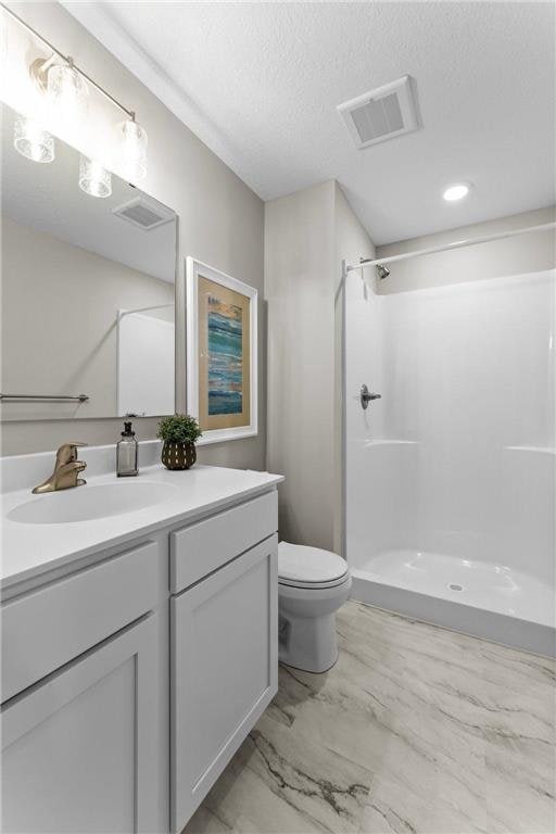 bathroom with vanity, a textured ceiling, toilet, and walk in shower