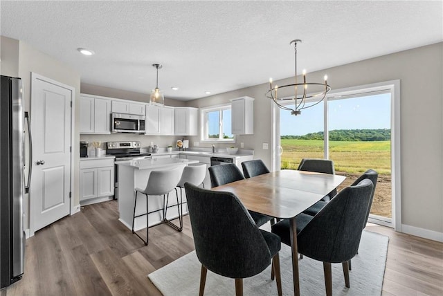 dining space with hardwood / wood-style floors, an inviting chandelier, and a wealth of natural light