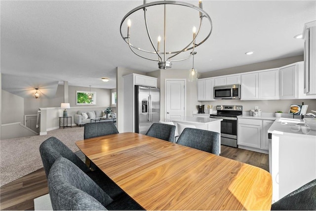 dining space featuring dark hardwood / wood-style floors, sink, and an inviting chandelier