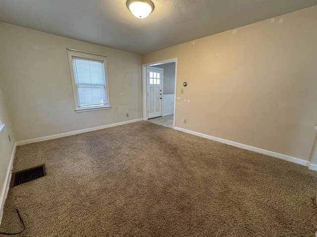 empty room featuring carpet, visible vents, and baseboards