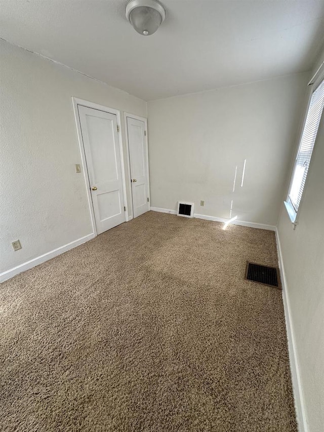 carpeted empty room with baseboards and visible vents