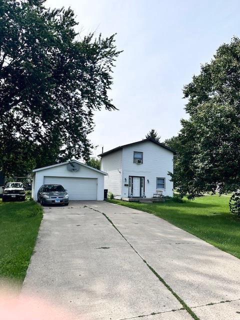 view of front of house with a garage, an outdoor structure, and a front yard