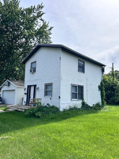 exterior space with an outbuilding, a garage, a front lawn, and cooling unit