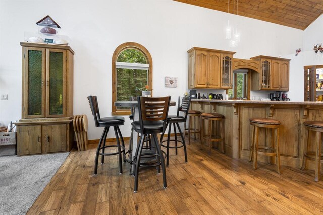 dining space featuring hardwood / wood-style floors, high vaulted ceiling, and brick ceiling