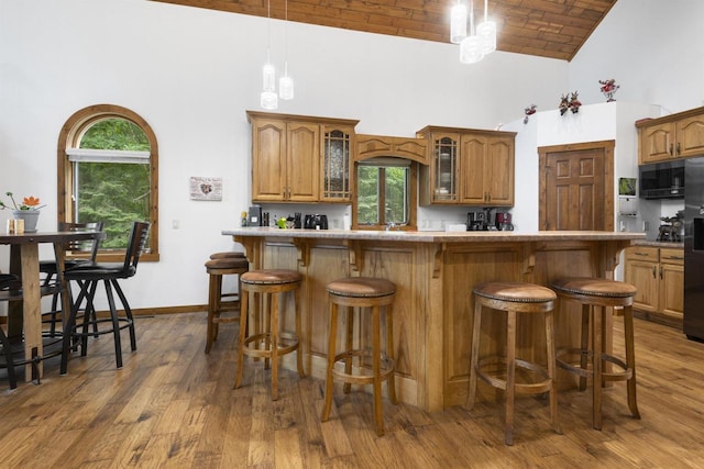 kitchen with dark hardwood / wood-style floors, a kitchen breakfast bar, brick ceiling, and high vaulted ceiling