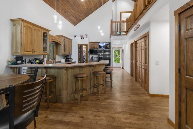 kitchen with a breakfast bar, black fridge, kitchen peninsula, and high vaulted ceiling