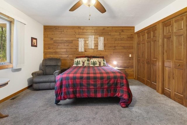 carpeted bedroom featuring a closet, ceiling fan, and wood walls