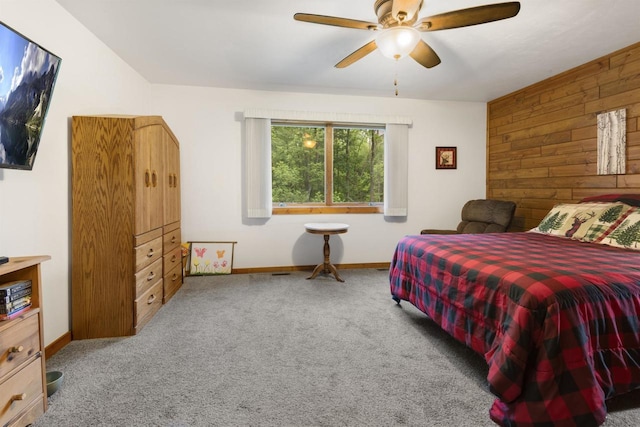 bedroom featuring carpet, wood walls, and ceiling fan