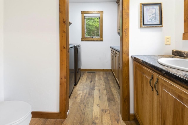 bathroom with independent washer and dryer, vanity, toilet, and wood-type flooring