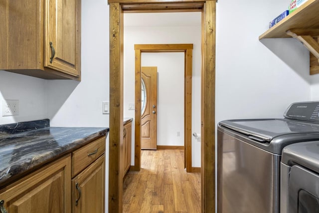 washroom with cabinets, light hardwood / wood-style floors, and washer and clothes dryer