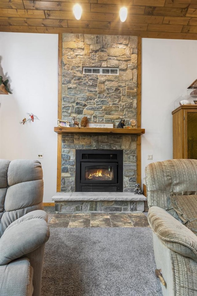 living room featuring a stone fireplace and wooden ceiling