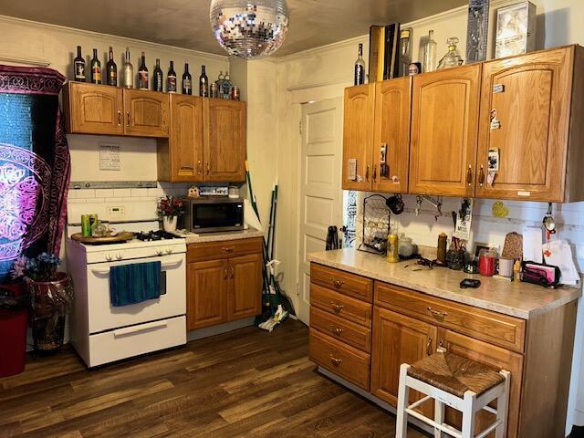 kitchen with dark hardwood / wood-style floors, white gas stove, an inviting chandelier, and decorative backsplash