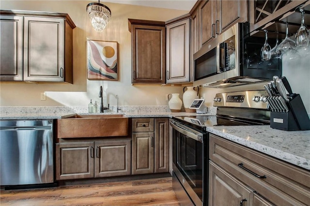 kitchen with sink, hanging light fixtures, an inviting chandelier, hardwood / wood-style floors, and appliances with stainless steel finishes