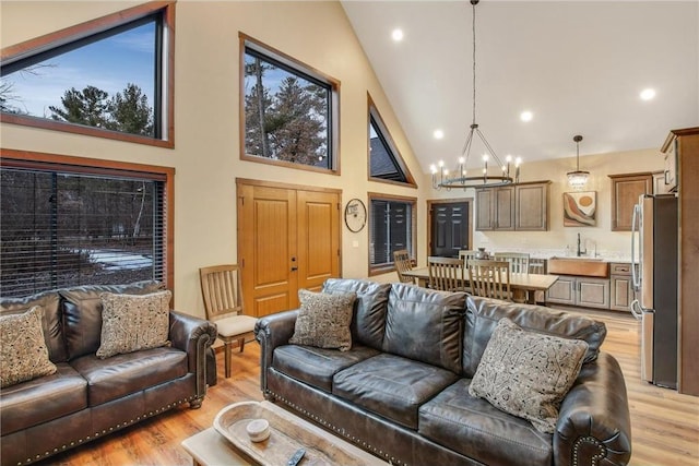 living room with light wood-type flooring, sink, and high vaulted ceiling