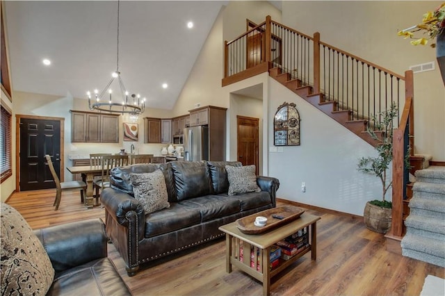 living room with wood-type flooring, high vaulted ceiling, and an inviting chandelier