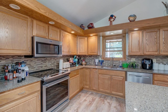 kitchen featuring light stone countertops, sink, stainless steel appliances, tasteful backsplash, and lofted ceiling