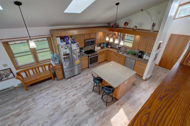 kitchen featuring vaulted ceiling with skylight, sink, backsplash, hanging light fixtures, and stainless steel appliances