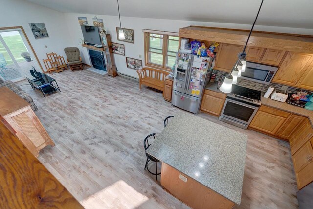 kitchen featuring pendant lighting, lofted ceiling with skylight, sink, decorative backsplash, and stainless steel appliances