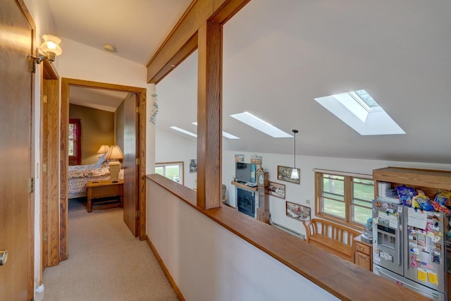 hall featuring vaulted ceiling with skylight and light carpet