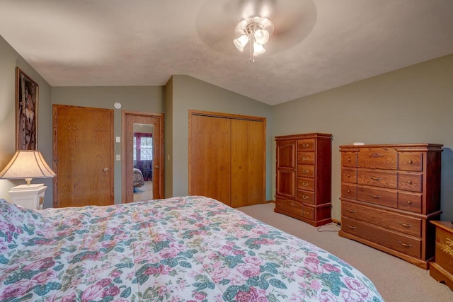 carpeted bedroom with vaulted ceiling, a closet, and ceiling fan