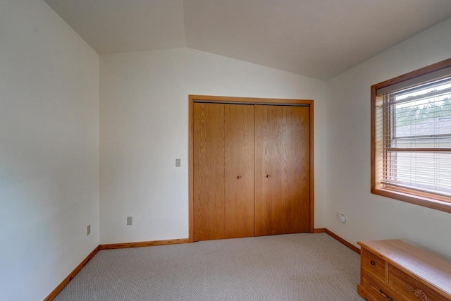 unfurnished bedroom with vaulted ceiling, light colored carpet, and a closet