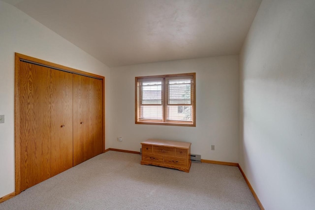 unfurnished bedroom featuring carpet, lofted ceiling, baseboard heating, and a closet