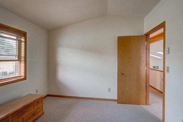 empty room with light colored carpet and vaulted ceiling