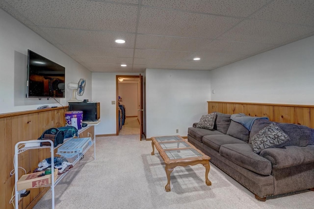 carpeted living room with a paneled ceiling and wood walls