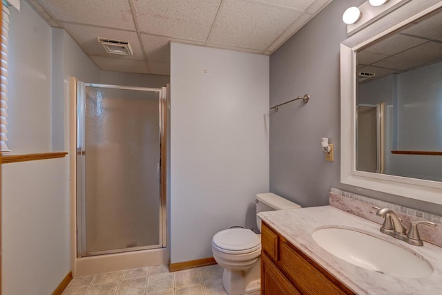 bathroom featuring a paneled ceiling, vanity, toilet, and a shower with door