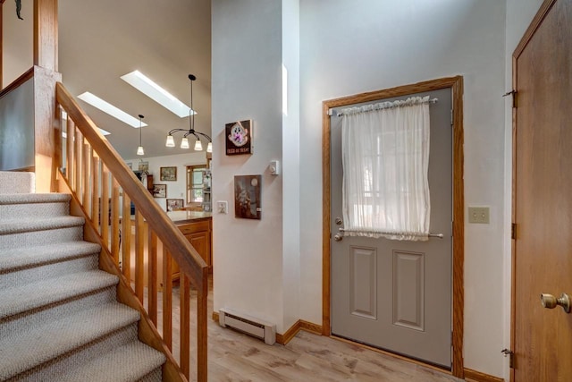 entryway featuring a high ceiling, a skylight, baseboard heating, and light hardwood / wood-style floors