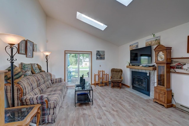 living room with light wood-type flooring, a skylight, a tile fireplace, a baseboard radiator, and high vaulted ceiling