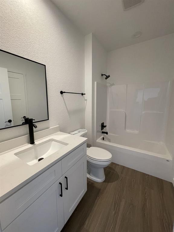 full bathroom featuring  shower combination, toilet, hardwood / wood-style floors, and vanity