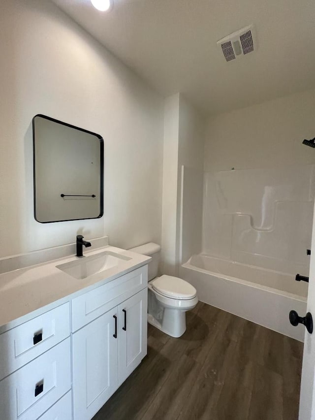 full bathroom with washtub / shower combination, vanity, toilet, and hardwood / wood-style floors