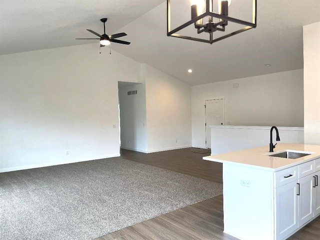 kitchen with ceiling fan with notable chandelier, white cabinetry, an island with sink, lofted ceiling, and sink