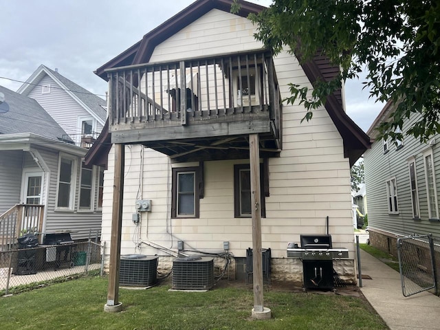 rear view of house with a lawn, a balcony, and central air condition unit